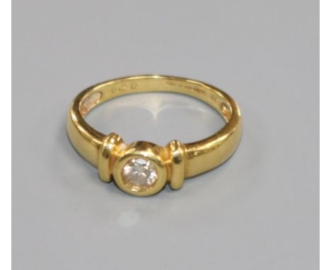 A modern 18ct gold and collet set solitaire diamond ring, size M.