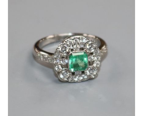 An Art Deco style white gold, emerald and diamond cluster ring, size M.