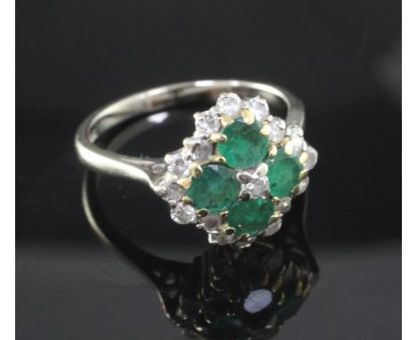 An 18ct white and yellow gold, emerald and diamond cluster ring, claw set with four emeralds and seventeen diamonds, size T/U