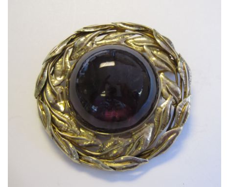 An Arts and Crafts Amethyst Brooch the large cabochon within pierced foliate silver gilt frame
