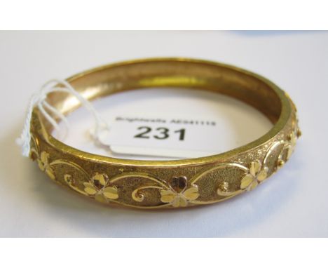 A textured gold rigid Bangle embossed flowers, approx 19.50gms