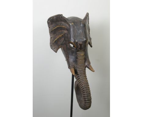 A carved anatomically accurate Face Mask in the form of an Elephant with ribbed Trunk reaching back towards the hinged jaw in