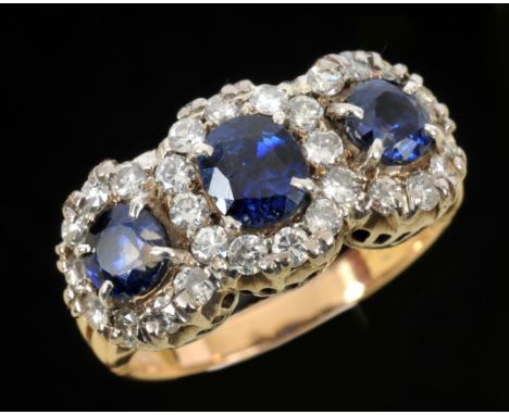 A Sapphire and Diamond Ring claw-set one oval-cut and two circular-cut sapphires each within frame of brilliant-cut diamonds,