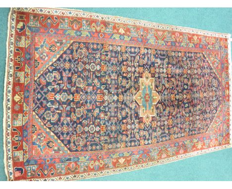 An antique Persian small Carpet with herati pattern on an indigo ground, the principal red ground border with stylised horns,