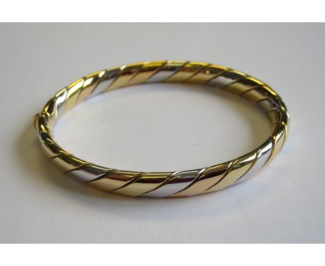 A tri-coloured 18ct gold hinged Bangle
