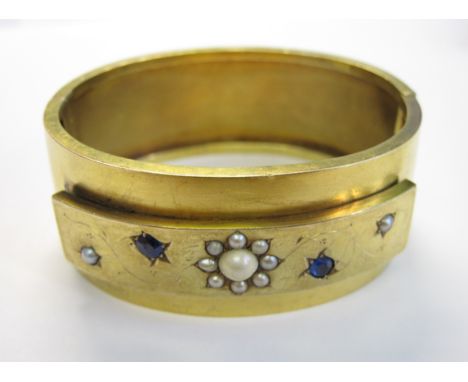 A gold hinged Bangle the front set seed pearls and two circular-cut sapphires, approx 38.30gms