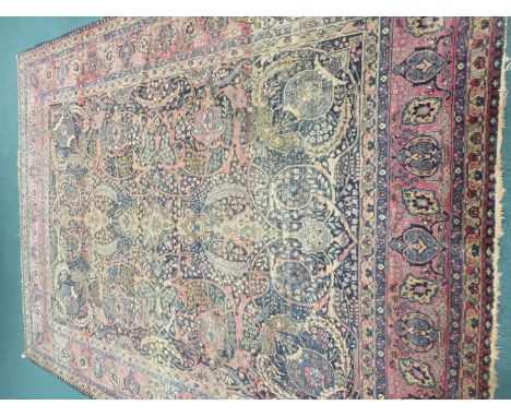 A 19th Century Kirman Carpet with all-over floral and leafage design on an indigo ground, the principal border with palmettes