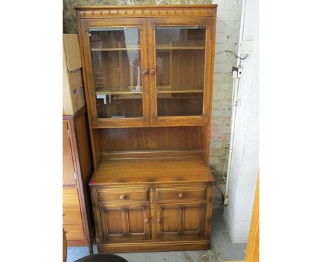 An Ercol Golden Dawn elm bookcase cabinet with twin glazed doors, two drawers and a pair of doors, 77 high, 38 1/2 wide