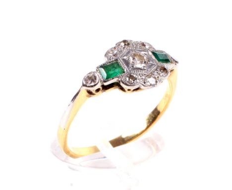 An Art Deco period emerald and diamond cluster ring. Centred with a small early modern round brilliant diamond between small 