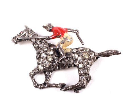 A vintage paste racehorse & jockey brooch. The jockey in red enamelled racing colours, the galloping horse pave set with near