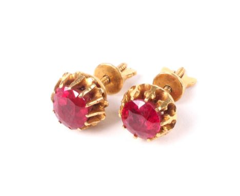 A pair of Middle Eastern yellow metal and ruby single stone stud earrings. Each set with either a round or a slightly cushion