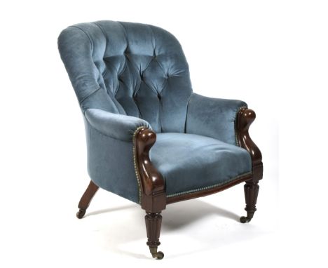 A late Victorian button back library chair.The padded arms enclosing a sprung seat, raised on turned mahogany supports with c