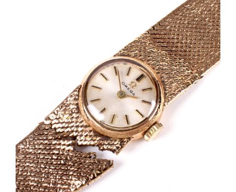 A vintage 9ct gold Omega manual wind ladies wristwatch. The silvered dial with batons denoting hours, on original textured go