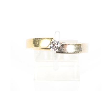 A diamond solitaire ring. The round brilliant approx. 0.20cts, compression-set to an off-set bi-colour square-section band, s