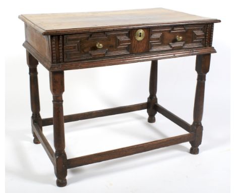 A 17th century oak side table. With geometric moulded drawer front and later brass handles and escutcheon, on turned baluster