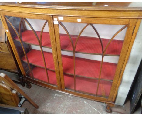 A 1.2m vintage oak display cabinet with material lined interior enclosed by a pair of Gothic beaded glazed panel doors, set o