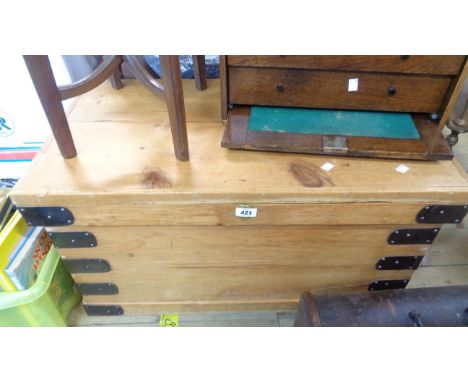 An 81cm old waxed pine lift-top trunk with metal bound corners and flanking iron drop handles
