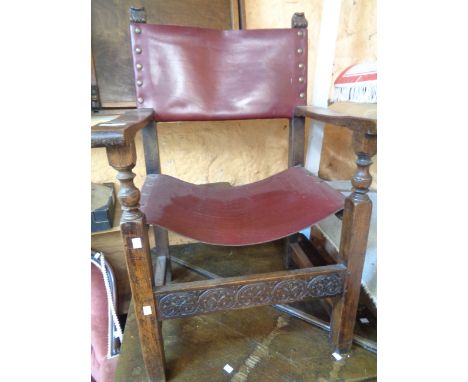 A vintage oak framed elbow chair with studded red leather upholstered back and seat