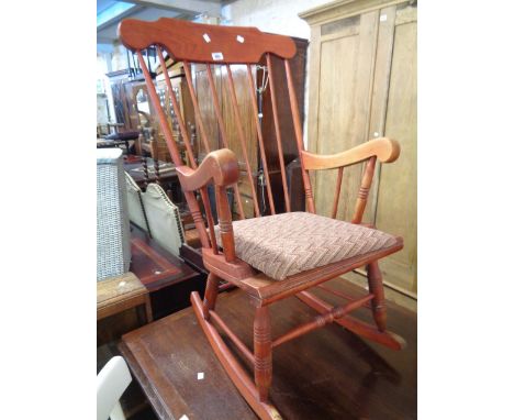 A modern stained wood high stick back rocking chair with mis-matched upholstered seat panel, set on turned supports