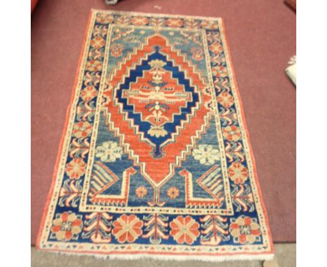 A vintage Afghan handmade wool rug with central diamond motif on a red and blue ground within a wide floral border - 1.5m X 9
