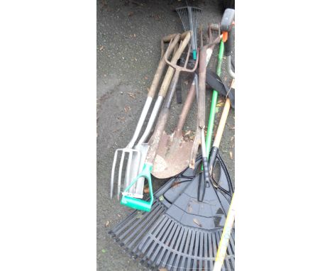 A quantity of assorted garden tools including rakes, spades, etc.