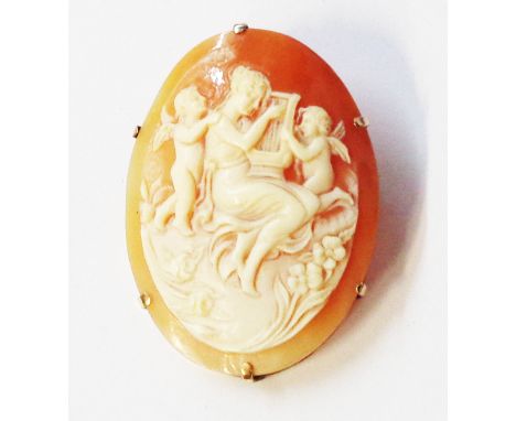 A yellow metal framed oval shell cameo brooch, depicting Calliope playing a harp with attendant cherubs
