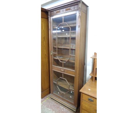 A 79cm early 20th Century stained oak book cabinet with offset cornice, blind fretwork frieze and applied decoration, adjusta