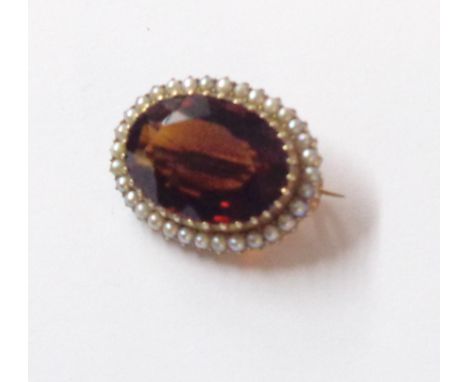 A 2.5cm marked 9ct framed oval brooch, set with central Madeira citrine within a seed pearl border