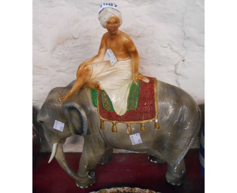 A vintage plaster figurine depicting a young Indian boy seated upon an elephant