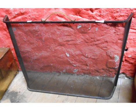 An old wrought iron and mesh fire screen with curved brass handle