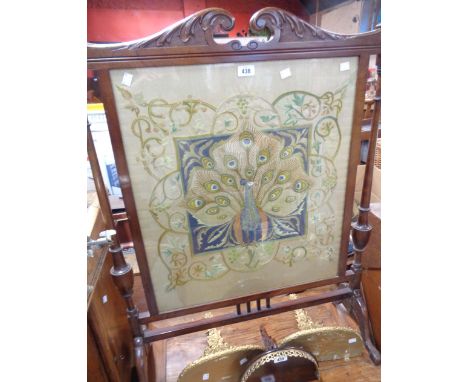 An early 20th Century mahogany framed fire screen with ornate pediment, turned finials and flanking turned supports, with pea