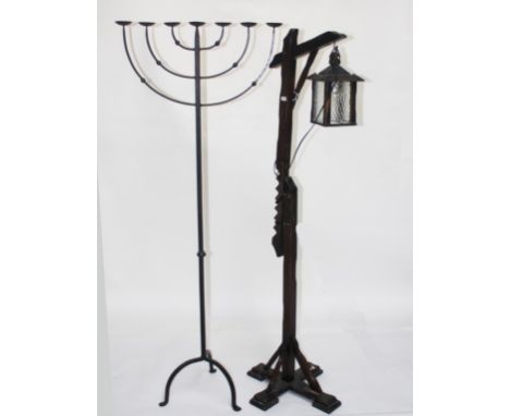 A WOODEN TELESCOPIC SIGNPOST STANDARD LAMP,  with hanging lantern, on cruciform base; together with a wrought iron Menorah st