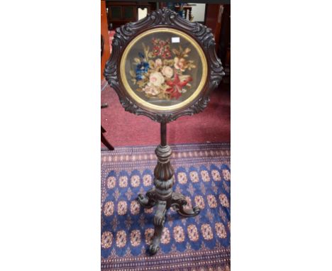 A VICTORIAN WALNUT POLE SCREEN,  with wool tapestry panel depicting flowers, inside a circular scroll moulded frame, on a tri