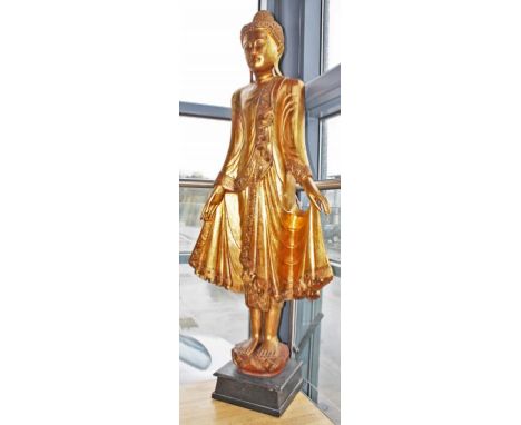 A LARGE CARVED GILT WOOD AND JEWELED FIGURE OF THE FEMALE  DEITY,  with jeweled tiara and jeweled sash, her two hands support