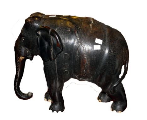 A HEAVY EBONY CARVED ELEPHANT, modelled with trunk lowered and ears back, 15'' (39cm) high, 19.5'' (50cm) wide. (1)