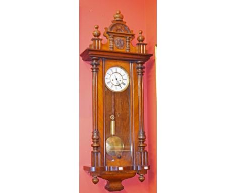 A LATE 19TH CENTURY WALNUT VIENNA WALL CLOCK, the arched top with urn finials above a circular enamel two-stage dial, with Ro