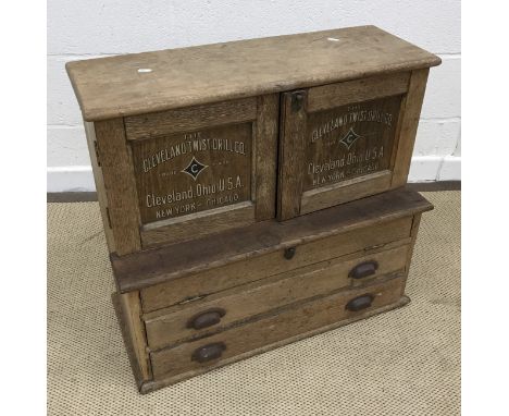 A vintage / early 20th Century oak tool chest, the plain top over two cupboard doors with transfer inscription "The Cleveland