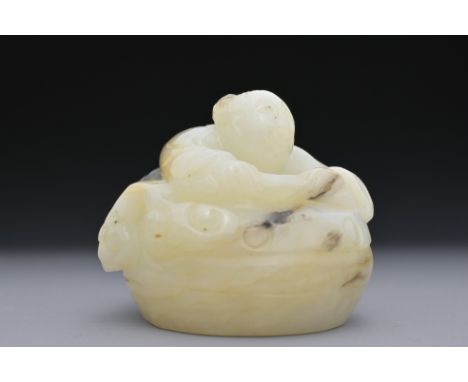A CHINESE GREENISH-WHITE AND BLACK JADE CARVING OF BOY ON DRUM. The boy lent over a drum with lingzhi fungus. 4.5cm length.Ov