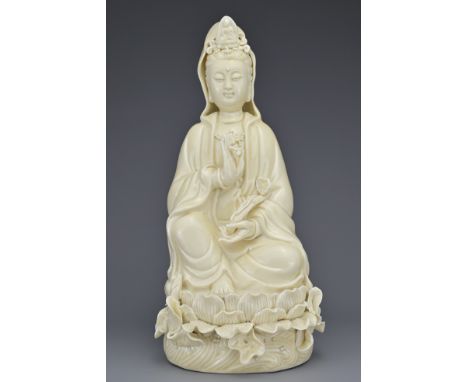 A CHINESE PORCELAIN FIGURE OF GUANYIN. The figure seated on a lotus base holding a ruyi sceptre and pearl, covered in an ivor