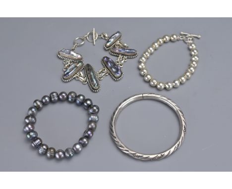 A GROUP OF FOUR SILVER AND PEARL BRACELETS AND BANGLE. To include a cylindrical bangle, a beaded bracelet and two other brace