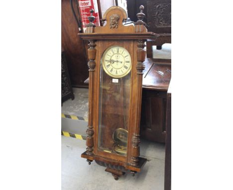 Late 19th Century / early 20th Century walnut cased Vienna wall clock, the shaped maskhead surmount above a glazed door, the 