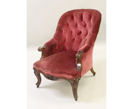 Victorian carved walnut and button upholstered tub shaped drawing room chair with a floral carved frieze and cabriole support