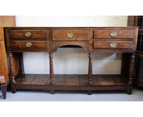 George III oak dresser base with an arrangement of five drawers with oval brass handles, surrounding a central kneehole above