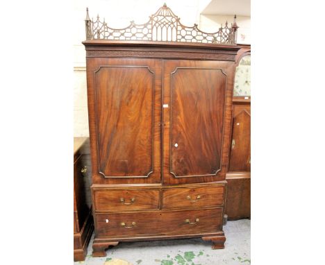 George III mahogany linen press with an open and blind fretted cornice above two panel doors enclosing linen slides, above tw