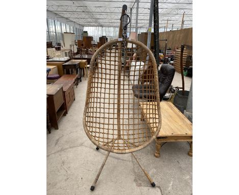 A SUSPENDED WICKER HAMMOCK CHAIR ON TRIPOD SUPPORT 
