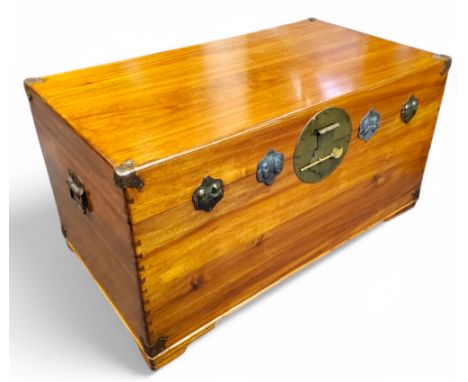 A Chinese camphor wood trunk, carrying handles to sides, bold circular escutcheon, 52cm high, 96cm wide, 53cm deep, 20th cent