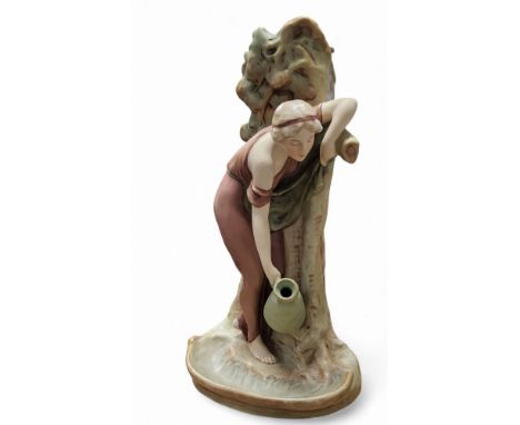 An early 20th century Royal Dux spill vase, after Diabrich, modelled as a maiden collecting water with an amphora from a stre