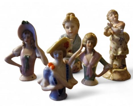 A continental porcelain pin cushion half doll, in 18th century dress; two others similar;&nbsp; a German figure,&nbsp; of a g