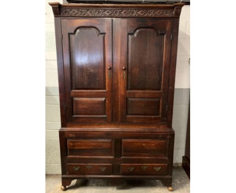 An 18th century and later stained oak double wardrobe, the top with a carved frieze, with two panel doors below and two short