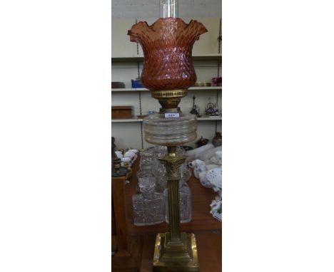 An oil lamp with frilled ruby glass shade, clear glass font and brass Corinthian column base 